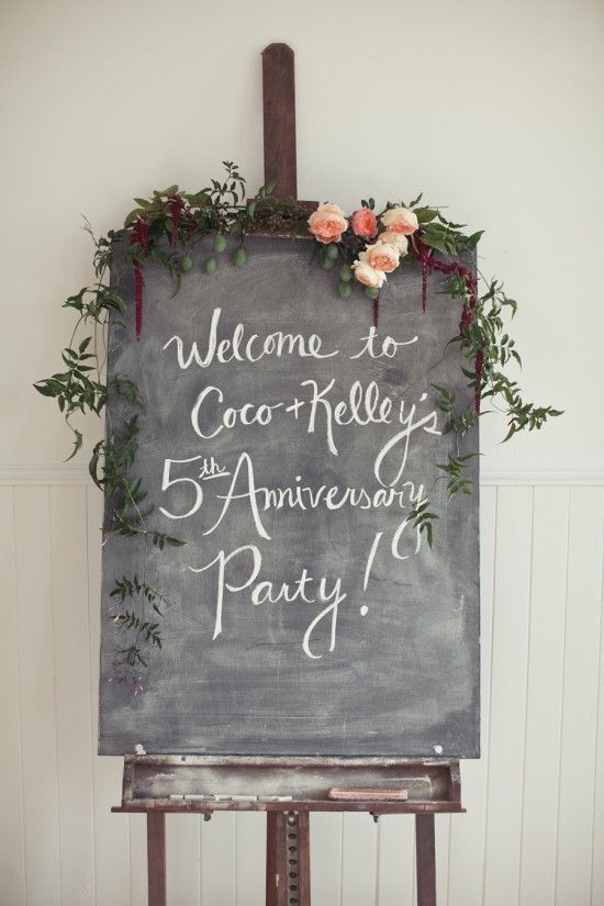 A chalkboard held up with a silver easel with dripping vine and purple and green