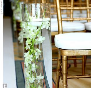 Ten cylinder vases with submerged orchids and floating candles lined the aisle a