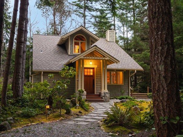 small house in woods with warm glow from front door