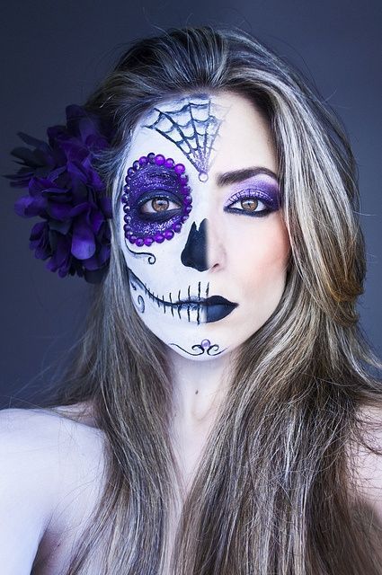 Creative purple half Dia De Los Muertos make-up with purple crystal accents, tit