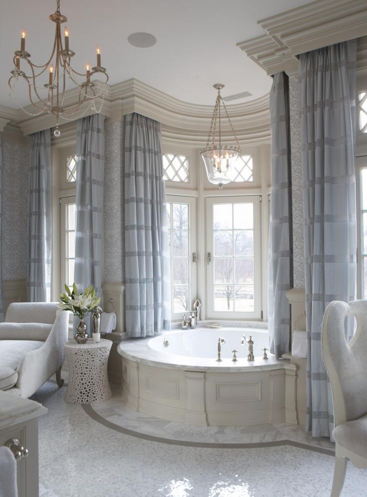 Very elegant bathroom design. The circular bathtub is the focal point of the room surronded my large windows. The drappery and fabric chaise lounge give the room a very soft romantic