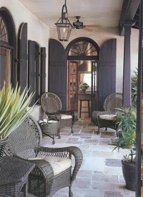 Grey flagstone floor, French doors with grey shutters and grey rattan furniture. Just