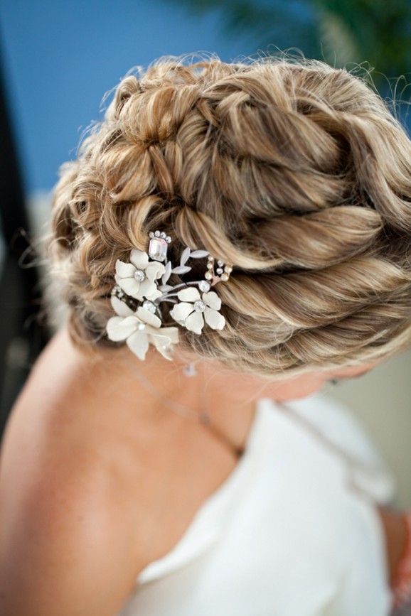 Sections of hair are curled and pinned back into a low nest of curls. Elegant and romantic look for long