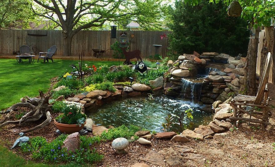 A half circle of retaining wall brick in back built up with clay and dirt in front pvc pipe runs from skimmer box to top of pond creates the waterfall… pond liner and donated rock… 4 ft deep and