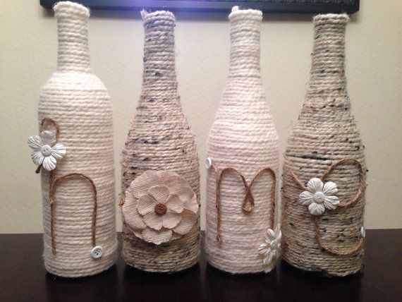 These up cycled wine bottles are delicately wrapped in neutral colored yarn then adorned with buttons and flowers to say either