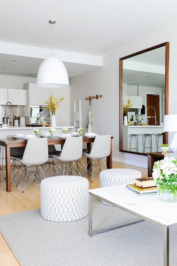 Modern dining space beside kitchen with modern light fixture and large mirror
