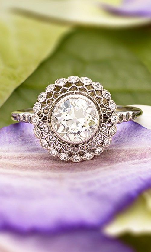This truly exceptional vintage-inspired ring encircles a bezel set diamond with lavishly detailed latticework and a halo of