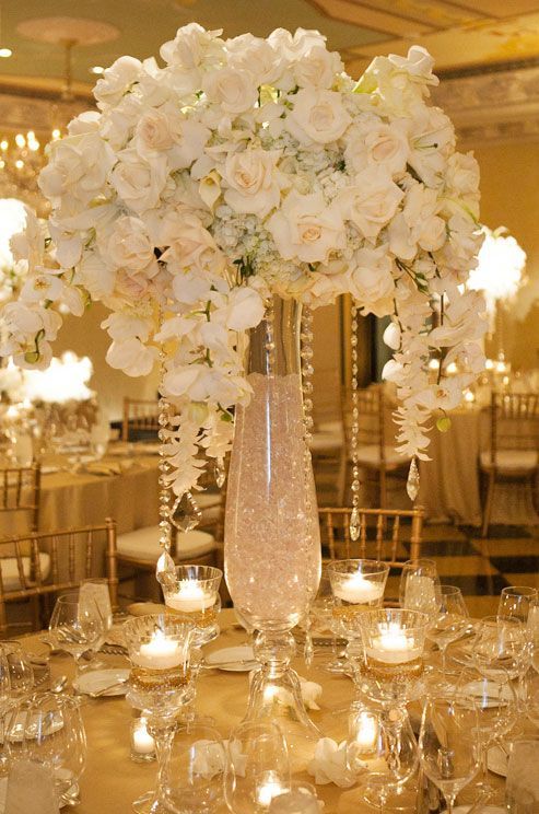 This grand centerpiece is a definite crowd pleaser, the tall vase is filled with crystals and accented by crystal strands dripping