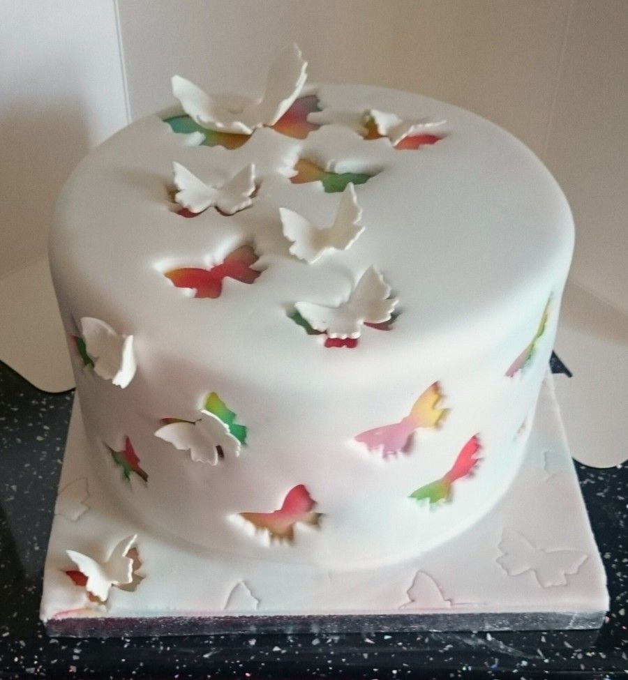 airbrushed cake covered in white fondant with butterflies cut out…