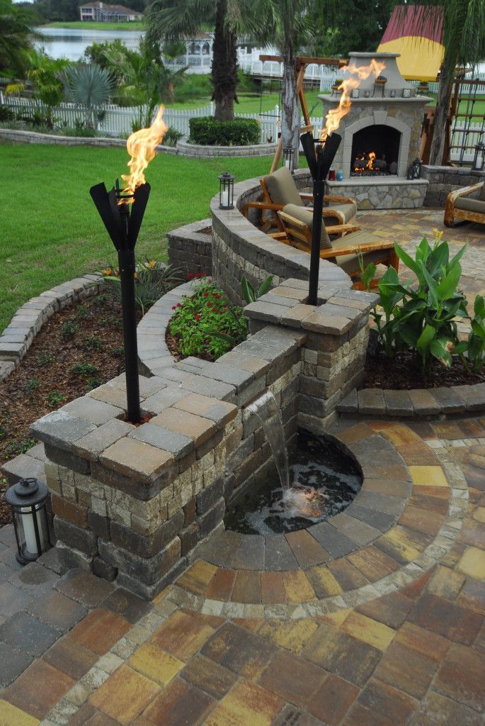 Beautiful back patio. Water-feature, fireplace & nice touch with the torches.