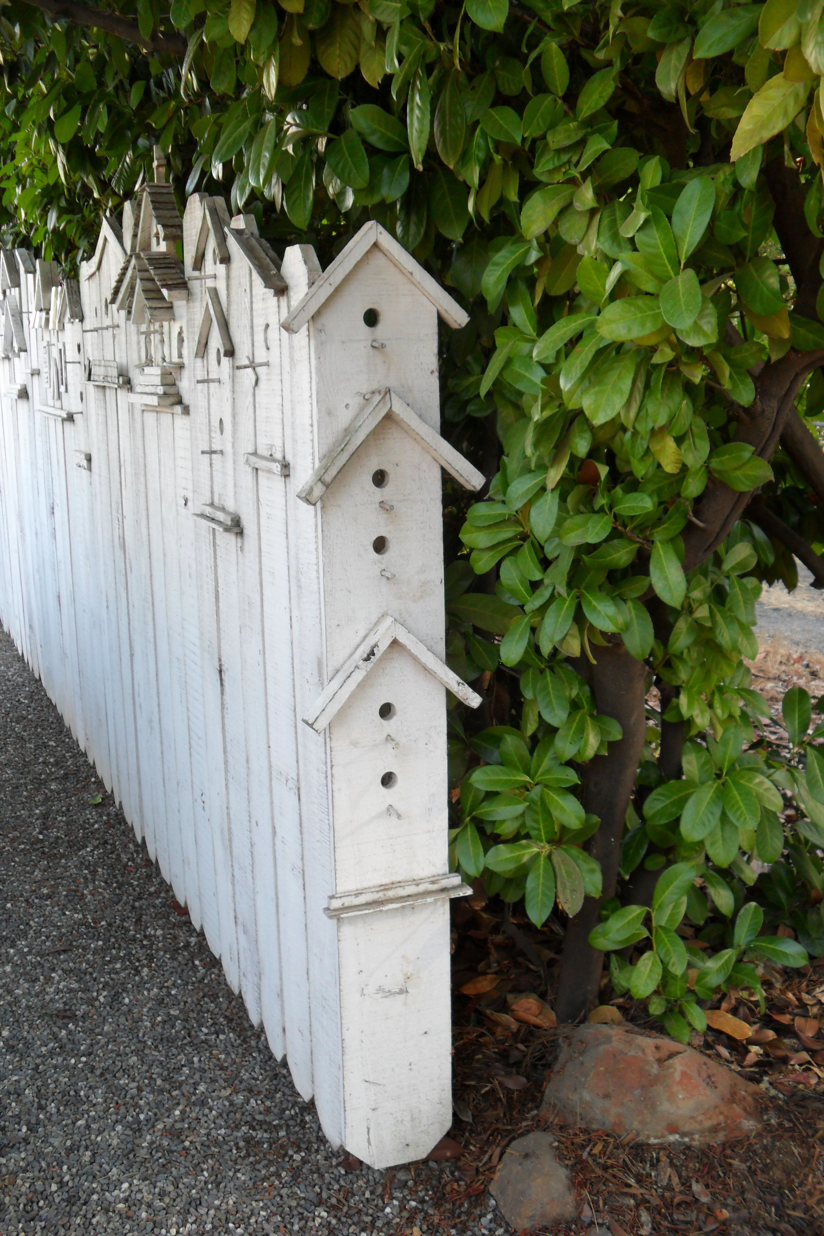 Add a simple side piece of wood to an ordinary wooden fence to create a birdhouse fence, by drilling h