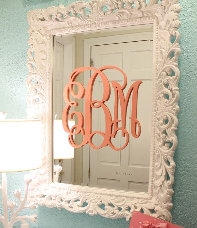 baby’s initials painted coral on a framed mirror in an aqua blue nursery