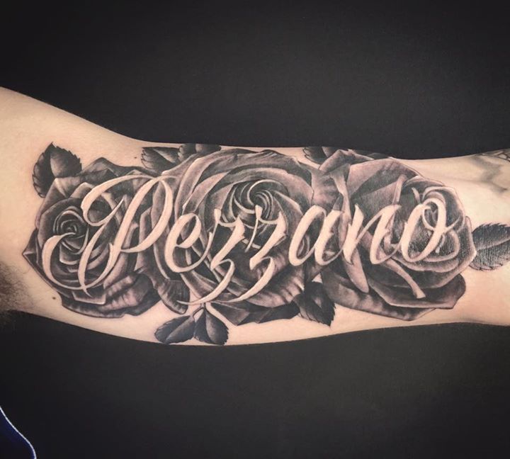Black and grey roses tattoo with last name across. On the arm
