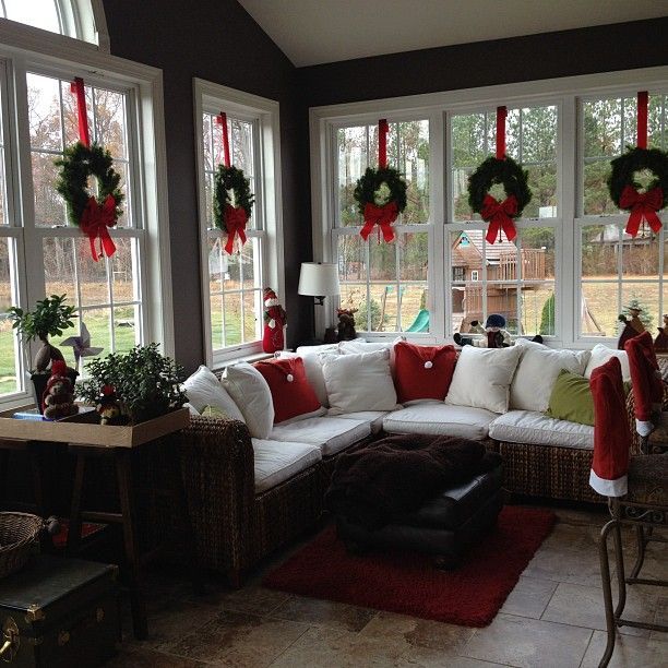 Love the wreaths suspended with red ribbon in the windows of this sunroom decorated for the Christmas season.
