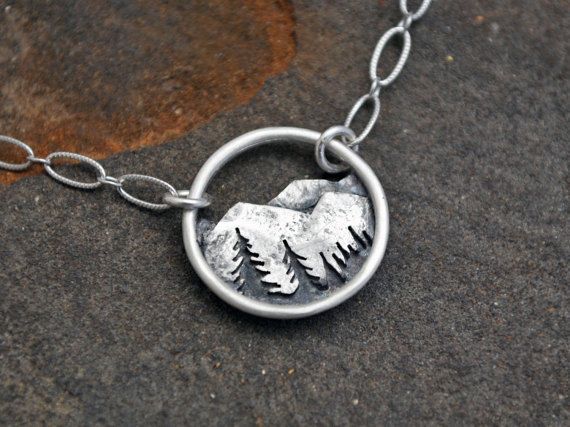 This little pendant features a rocky mountain range with a silhouetted tree line. It is all sterling silver and completely