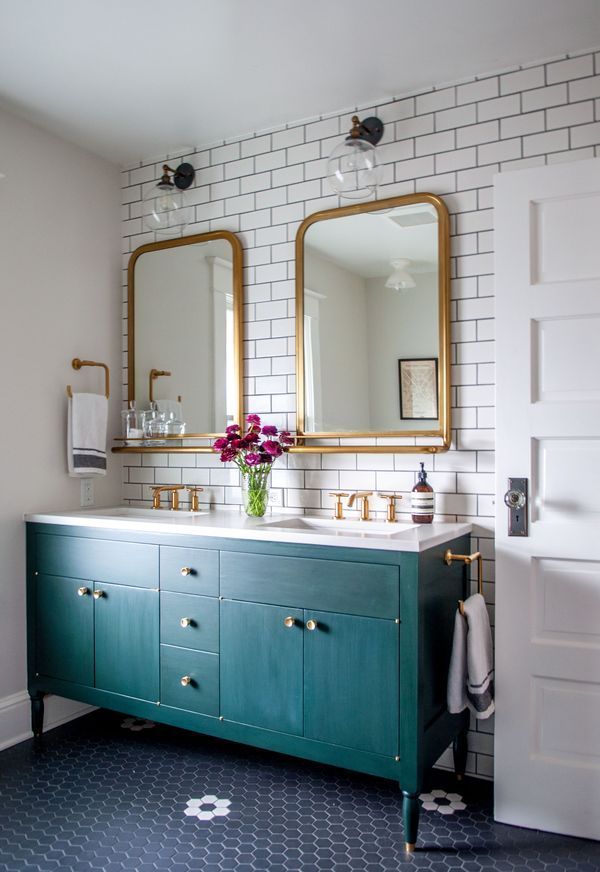 Eclectic bathroom with green cabinet, dual sinks, and subway tile