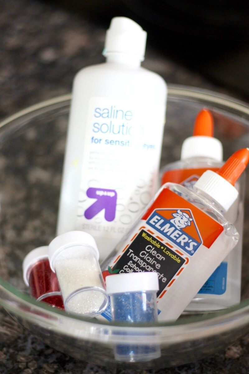 Saline solution slime recipe ingredients include clear glue, saline solution or contact solution, water, baking soda, and glitter