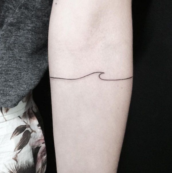 Minimalist wave tattoo on the arm. You can see a single line with a single wave in the middle. This is a perfect design when you