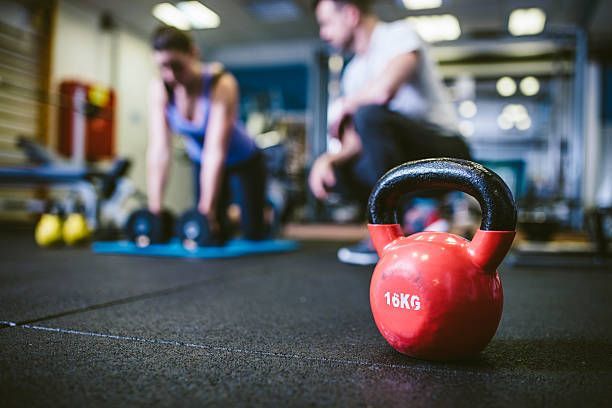 Kettlebell on gym floor. Young woman exercising with personal trainer... -   5 fitness Equipment photography ideas